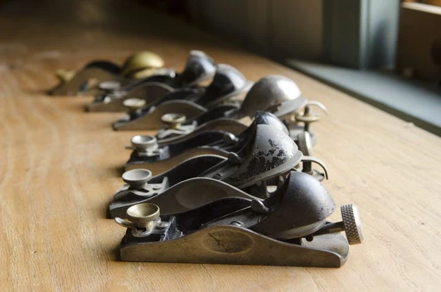 Antique Stanley Block Planes Sitting On A Woodworking Workbench In A Row