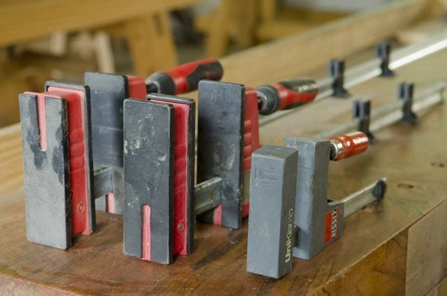 Bessey Parallell Bar Woodworking Clamps Sitting On A Woodworking Workbench