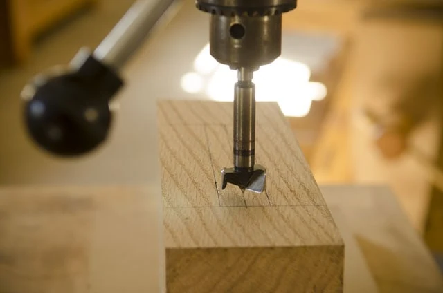 Forstner Bit In A Drill Press Ready To Bore Out A Mortise On An Oak Board