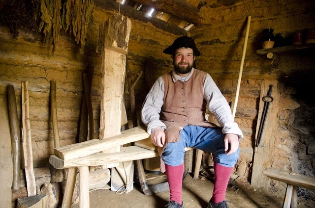 Colonial Man Sitting On A Woodworking Shaving Horse At The Frontier Culture Museum