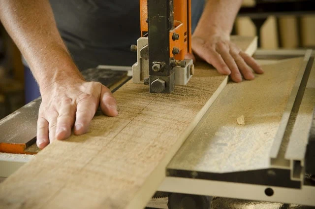 Woodworker Ripping A Board On A Grizzly Band Saw