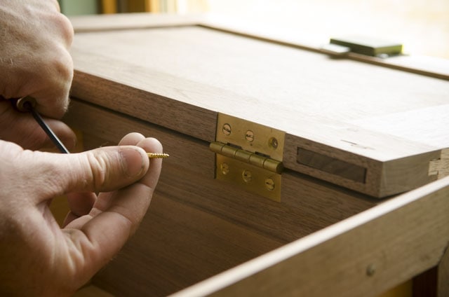 Woodworker Adding Brass Screws Into A Cupboard Door Brass Hinge With Clocked Screws